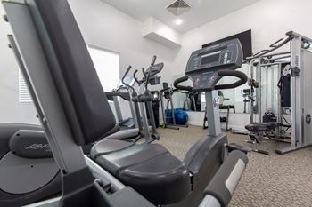 A gym with treadmills, elliptical machines, and other exercise equipment. at Bluffs Apartments, Bluffdale, UT